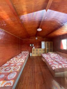 two beds in a room with wooden walls and wooden floors at Chatka pri vode aj pre rybárov 3 in Galanta