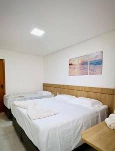 two beds in a room with white sheets at Giacomelli Plaza Hotel in Rio Verde