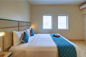 a bedroom with a large bed with two windows at Hotel Vilmaris Breeze in Calangute +27 photos