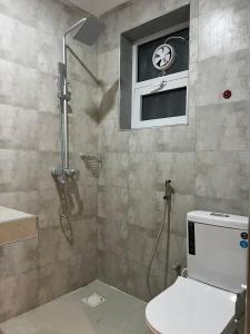 a bathroom with a shower and a toilet and a window at Capri Hills 4 in Mwanza