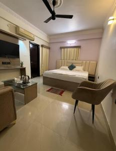a bedroom with a bed and a chair and a table at Hotel Alaska in Patna