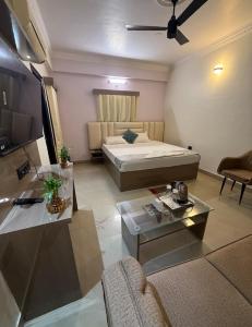 a room with a bed and a couch and a tv at Hotel Alaska in Patna