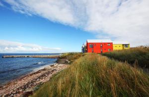 a red and yellow building on a hill next to the water at Pennan - 2 Bed Luxury Apartment by Together Travel in Wick