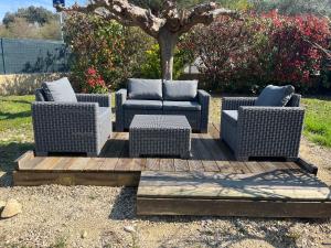 three wicker chairs and a table on a wooden deck at Gîte Ruoms in Ruoms