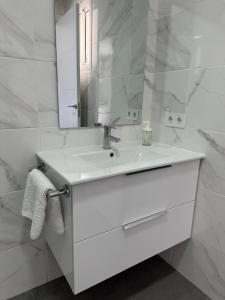 a white bathroom with a sink and a mirror at Ático Rocamar in La Restinga +19 photos
