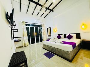 a bedroom with a large bed with purple sheets at Heriance Anuradhapura in Tammannewa