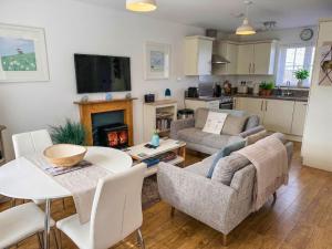 a living room with a couch and a table with a fireplace at Mallow Cottage in Camber