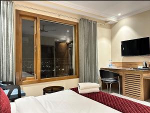 a hotel room with a bed and a desk and a window at Shree Vatika in Rishīkesh