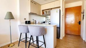 a kitchen with two bar stools and a refrigerator at Gran espacio para descansar cerca de todo in Concón