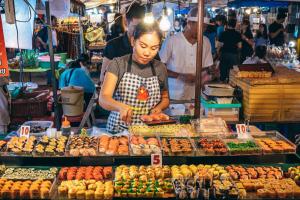 a woman standing in a market selling food at Allrange Home 5 bedroom for 10 guests in Chiang Mai