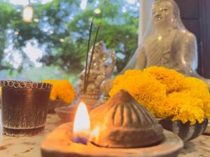 a candle on a table with flowers and a statue at Heriance Anuradhapura in Tammannewa +17 photos