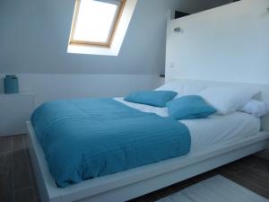 een wit bed met blauwe lakens en een raam bij Gite entre Terre et Mer in Ploumilliau