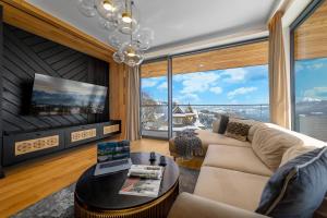 a living room with a couch and a table at Salamandra Luxury Villas with Jacuzzi by BQQK in Kościelisko