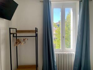 a window with blue curtains next to a radiator at Hôtel de Paris - Dijon Centre Gare in Dijon +24 photos