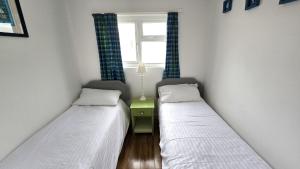two beds in a small room with a window at Chalet 151, Perran Sands in Perranporth