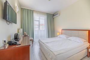 a bedroom with a bed and a desk with a television at Hotel Balkan in Gabrovo