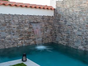 a swimming pool with a waterfall in a brick wall at El Refugio del Agua - Casa Rural in Valsequillo