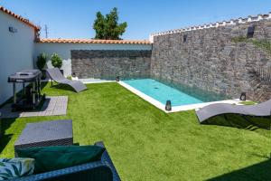 a backyard with a swimming pool and green grass at El Refugio del Agua - Casa Rural in Valsequillo