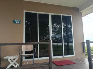 a building with glass doors and a chair on a deck at Sunset Beach House in Kudat +1 photo