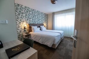 a hotel room with a large bed and a desk at Hotel Restaurant Au Riesling in Zellenberg