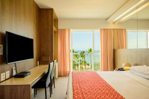 a hotel room with a desk and a bed and a television at Hotel Beira Mar in Fortaleza