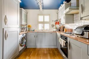 a kitchen with white cabinets and a washer and dryer at Main House in Rotherham