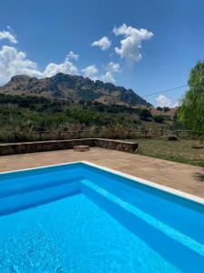 a blue swimming pool with a mountain in the background at Casa Fochita in Gratteri