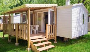 a small white house with a porch and a table at Camping le Lizot - Mobil home 3 pièces 4/6 personnes + TV MAE-8684 in Saint-Mandé-sur-Brédoire