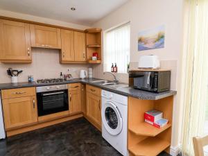 a kitchen with a washer and a sink and a microwave at The Beach Escape in Prestatyn