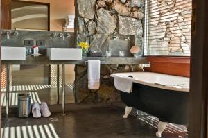 a bathroom with a tub and a stone wall at Awasi Mendoza in Ciudad Lujan de Cuyo +19 photos