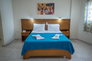 a bedroom with a blue bed with two towels on it at Cliff Bay Hotel by GHH in Paleros