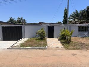 a white building with a gate and two plants at Studio spacieux Aéroport FHB in Abidjan