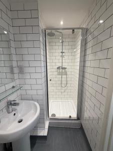 a white bathroom with a shower and a sink at The Brighton Hotel Seafront in Brighton & Hove