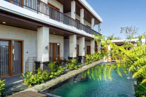 a hotel with a swimming pool in front of a building at Damara Ubud in Ubud