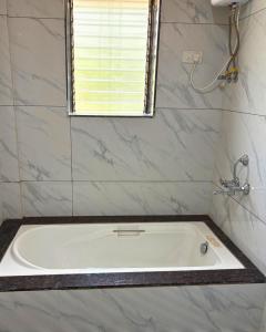 a white bath tub in a bathroom with a window at Private Rooms In Riverstone in Karjat