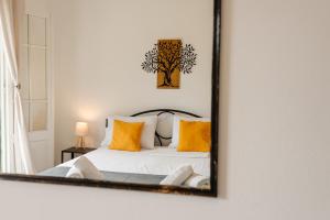 a mirror reflecting a bedroom with a bed with yellow pillows at Ionian Luxury Apartments in Perama +87 photos