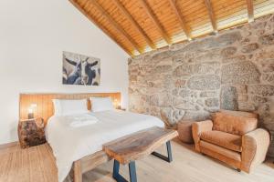 a bedroom with a bed and a stone wall at Banduja Reserve - Slow by nature in Celorico de Basto +126 photos