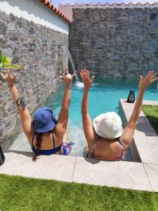 two people with their arms in the air near a swimming pool at El Refugio del Agua - Casa Rural in Valsequillo