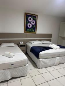 a bedroom with two beds and a painting on the wall at Pousada Tambaú in São Luís