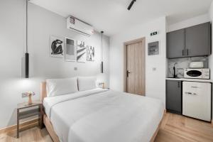 a bedroom with a white bed and a kitchen at Athenian Heart Suites in Athens