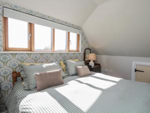 a bedroom with a bed with blue and white sheets and windows at The Hideaway Loft in Chippenham