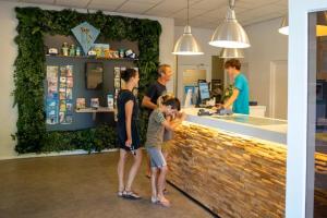 a group of people standing around a counter in a store at Mobilehome Super Mercure 2 Bedrooms Comfort Camping Scheldeoord in Baarland