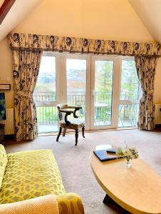 a living room with a table and a large window at Falls of Lora Hotel in Oban
