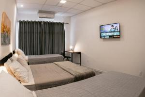 a hotel room with two beds and a flat screen tv at VILLA BILAC - Large Studios close to Vila Germânica in Blumenau