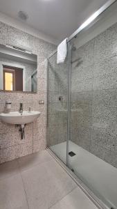 a bathroom with a glass shower and a sink at La Controra Hostel Naples in Naples