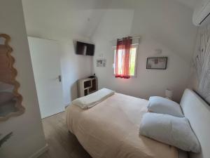 a white bedroom with a bed and a window at Le cocoon idyllique in Faverolles-sur-Cher