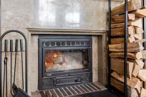 a fireplace with a fire in it next to a pile of logs at La Villa des Hauts Chênes in Bouillon