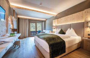 ein Hotelzimmer mit einem großen Bett und einem Schreibtisch in der Unterkunft Hotel Edelweiss in Prags