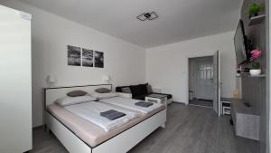 a white bedroom with a bed and a television at Grey Harmony Apartman in Debrecen