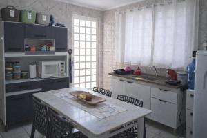 a kitchen with a table and a microwave at Quarto Sakura na Sakura House in Indaiatuba